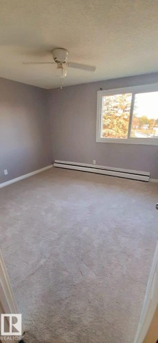 Spacious room with light-colored carpeting, a window providing natural light, and a ceiling fan - 307 6307 118 Ave, Edmonton, AB - Indoor Photo Showing Other Room