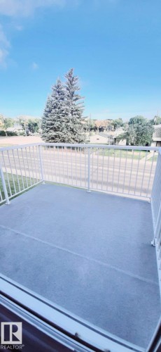 The property features a balcony with white railings and a view of mature trees and the surrounding neighborhood - 307 6307 118 Ave, Edmonton, AB - Outdoor