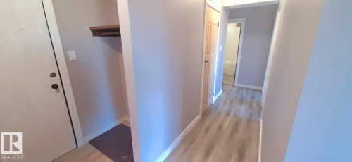 Hallway featuring light-colored flooring, a solid interior door, and a built-in shelving unit - 307 6307 118 Ave, Edmonton, AB - Indoor Photo Showing Other Room