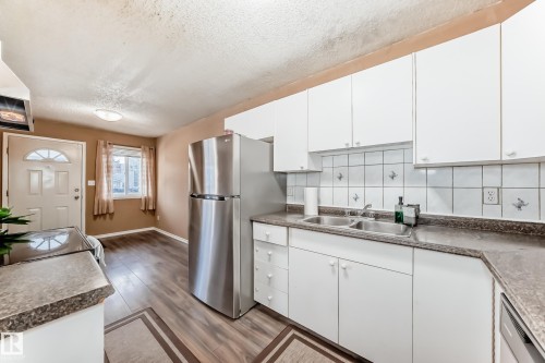 Kitchen featuring white cabinetry, a double basin sink, and a stainless steel refrigerator - 6 1580 Millwoods Road E, Edmonton, AB - Indoor Photo Showing Kitchen With Double Sink