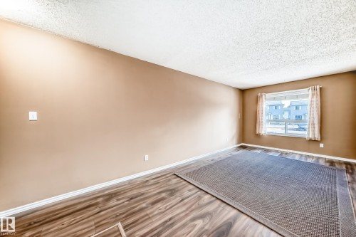 The room features wood-look flooring, a window with curtains, and neutral-toned walls - 6 1580 Millwoods Road E, Edmonton, AB - Indoor Photo Showing Other Room