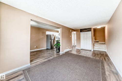 This interior features wood flooring, neutral tone walls, and white baseboards - 6 1580 Millwoods Road E, Edmonton, AB - Indoor Photo Showing Other Room