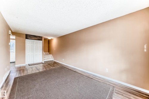 The living area features wood-look flooring and light-toned walls - 6 1580 Millwoods Road E, Edmonton, AB - Indoor Photo Showing Other Room
