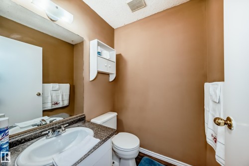 Bathroom featuring a vanity with a sink, a toilet, a wall-mounted storage cabinet, and a mirror with overhead lighting - 6 1580 Millwoods Road E, Edmonton, AB - Indoor Photo Showing Bathroom