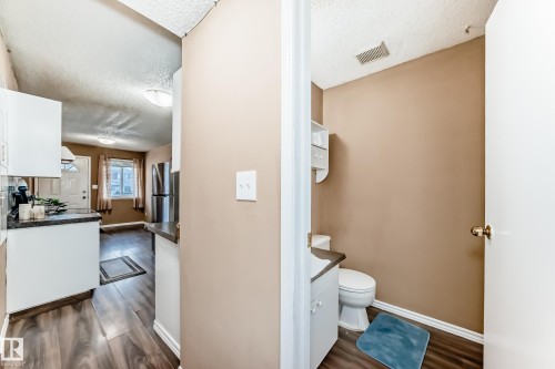 This property features a kitchen with white cabinetry, dark countertops, and stainless steel appliances - 6 1580 Millwoods Road E, Edmonton, AB - Indoor