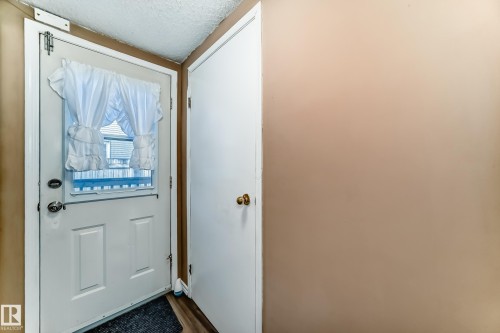 Entryway featuring a white door with a window and a white valance, alongside a light brown wall - 6 1580 Millwoods Road E, Edmonton, AB - Indoor Photo Showing Other Room