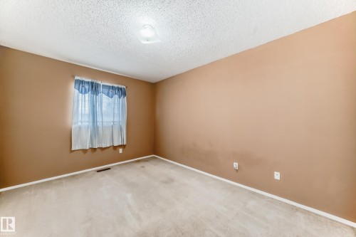 The room features a window providing natural light, a neutral-toned carpet, and walls painted in a warm tone - 6 1580 Millwoods Road E, Edmonton, AB - Indoor Photo Showing Other Room