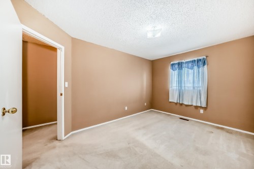 This interior space features light-colored carpeting, walls with a warm neutral paint, and white baseboards - 6 1580 Millwoods Road E, Edmonton, AB - Indoor Photo Showing Other Room