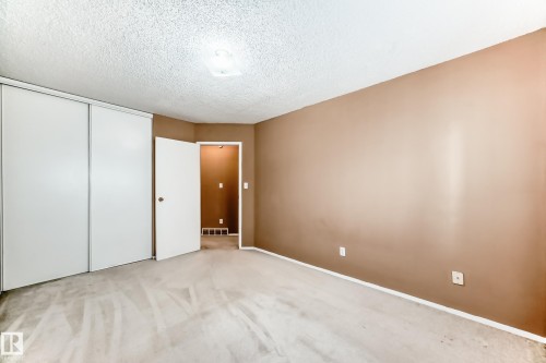 This room features light-colored carpeting, a ceiling light fixture, and a closet with sliding doors - 6 1580 Millwoods Road E, Edmonton, AB - Indoor Photo Showing Other Room