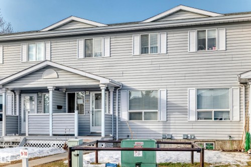The property features a multi-story exterior with light-colored siding, white window frames, and white shutters - 6 1580 Millwoods Road E, Edmonton, AB - Outdoor With Facade