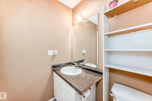 A bathroom featuring a vanity with an integrated sink, a rectangular mirror, and an overhead light fixture - 6 1580 Millwoods Road E, Edmonton, AB - Indoor Photo Showing Bathroom