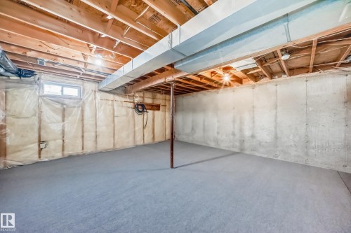 The property features an unfinished basement with exposed wooden beams, concrete walls, and a window providing natural light - 6 1580 Millwoods Road E, Edmonton, AB - Indoor Photo Showing Basement