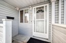 The property features a welcoming front entrance with light-colored siding, a window, and a white storm door with decorative glass - 6 1580 Millwoods Road E, Edmonton, AB  - Outdoor With Exterior 