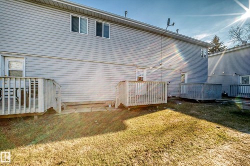 The property features light gray horizontal siding, several decks with wooden railings, and a grassy yard - 6 1580 Millwoods Road E, Edmonton, AB - Outdoor With Deck Patio Veranda With Exterior
