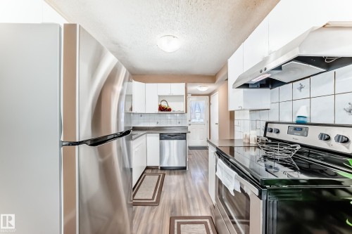 The kitchen features stainless steel appliances, including a refrigerator, dishwasher, and range - 6 1580 Millwoods Road E, Edmonton, AB - Indoor Photo Showing Kitchen