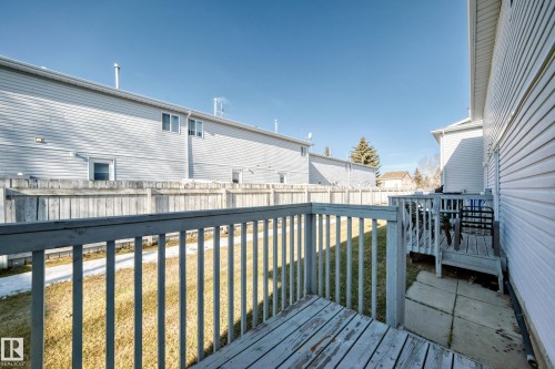 The property features a wooden deck with railing, a grass yard, and a separate concrete patio area - 6 1580 Millwoods Road E, Edmonton, AB - Outdoor With Deck Patio Veranda With Exterior