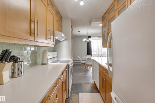 The kitchen features light wood cabinetry, white countertops, and a light green subway tile backsplash - 1202 9909 110 Street Nw, Edmonton, AB - Indoor Photo Showing Kitchen