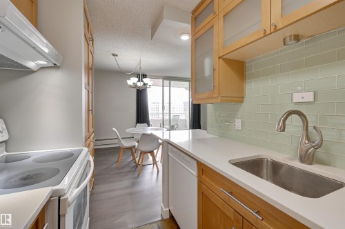 Kitchen featuring light wood cabinetry, a light green subway tile backsplash, a stainless steel sink with a gooseneck faucet, and white countertops - 1202 9909 110 Street Nw, Edmonton, AB - Indoor Photo Showing Kitchen
