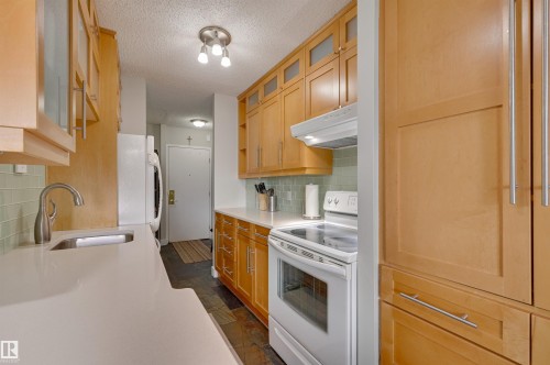 The kitchen features light wood cabinetry, a white countertop, and a light green tiled backsplash - 1202 9909 110 Street Nw, Edmonton, AB - Indoor Photo Showing Kitchen