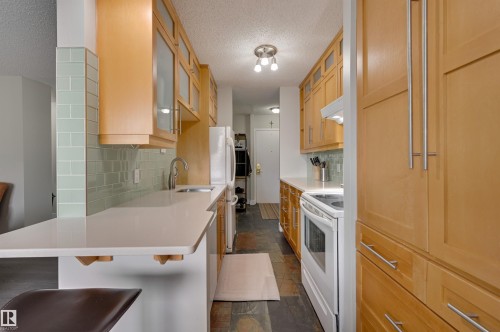 The kitchen features light wood cabinetry, a white countertop, and a light green tiled backsplash - 1202 9909 110 Street Nw, Edmonton, AB - Indoor Photo Showing Kitchen