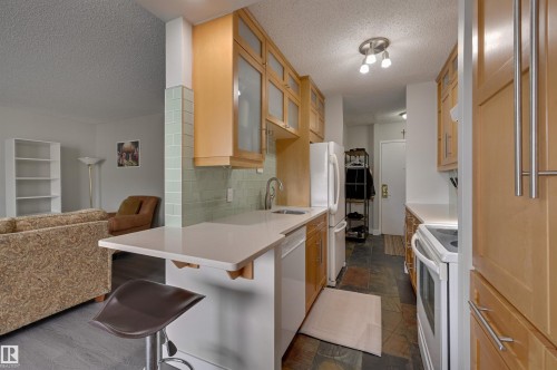 The kitchen features wooden cabinetry, white countertops, and a subway tile backsplash - 1202 9909 110 Street Nw, Edmonton, AB - Indoor Photo Showing Kitchen