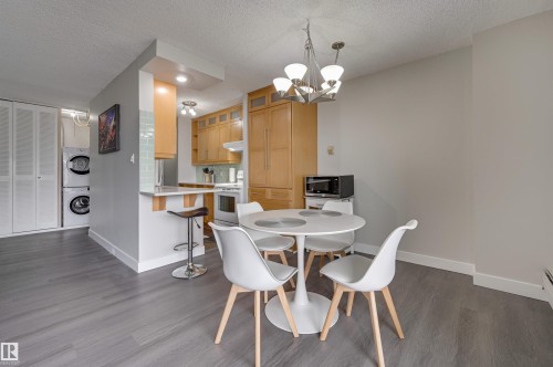 The kitchen features light wood cabinetry, a white stove, and a light blue tiled backsplash - 1202 9909 110 Street Nw, Edmonton, AB - Indoor Photo Showing Dining Room