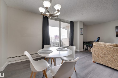 Dining area featuring a contemporary chandelier, grey flooring, and access to a balcony through sliding glass doors - 1202 9909 110 Street Nw, Edmonton, AB - Indoor Photo Showing Dining Room