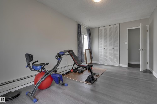 This room features light grey walls and grey wood-look flooring, creating a neutral palette - 1202 9909 110 Street Nw, Edmonton, AB - Indoor Photo Showing Gym Room