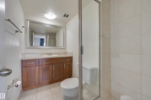 Bathroom featuring a vanity with wood cabinetry, a granite countertop, and a large mirror - 1202 9909 110 Street Nw, Edmonton, AB - Indoor Photo Showing Bathroom