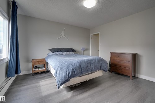 Bedroom featuring grey walls, a window with blue curtains, and wood-look flooring - 1202 9909 110 Street Nw, Edmonton, AB - Indoor Photo Showing Bedroom