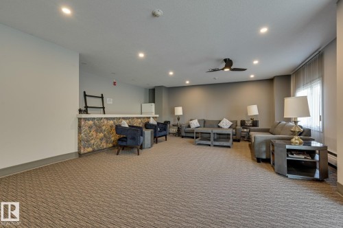 This expansive common area features patterned carpeting, recessed lighting, and a ceiling fan - 1202 9909 110 Street Nw, Edmonton, AB - Indoor