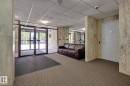 The property features a welcoming lobby area with glass entry doors, carpeted flooring, and stone-clad walls - 1202 9909 110 Street Nw, Edmonton, AB  - Indoor Photo Showing Other Room 