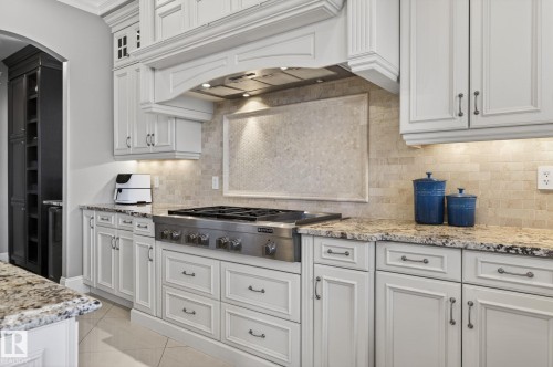 The kitchen features white cabinetry with dark hardware, granite countertops, a stainless steel range, and a tiled backsplash - 1413 Woodward Crescent, Edmonton, AB - Indoor Photo Showing Kitchen With Upgraded Kitchen