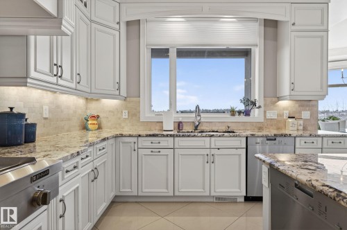 The kitchen features white cabinetry, granite countertops, a tiled backsplash, and stainless steel appliances - 1413 Woodward Crescent, Edmonton, AB - Indoor Photo Showing Kitchen With Upgraded Kitchen