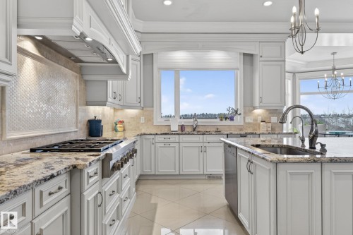 The kitchen features white cabinetry, granite countertops, a built-in range, a tile backsplash, and a window above the sink - 1413 Woodward Crescent, Edmonton, AB - Indoor Photo Showing Kitchen With Upgraded Kitchen