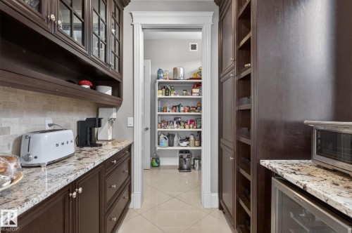 Well-appointed pantry featuring dark wood cabinetry, granite countertops, and light-toned tile flooring - 1413 Woodward Crescent, Edmonton, AB - Indoor Photo Showing Kitchen