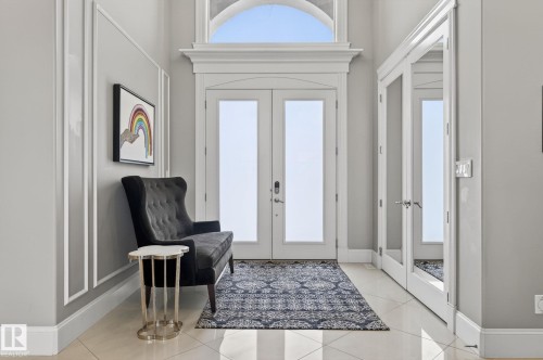 The entrance features a double door with glass panels and an arched transom window above, set against a light-colored wall with decorative molding - 1413 Woodward Crescent, Edmonton, AB - Indoor Photo Showing Other Room