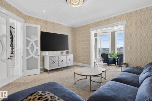 This living area showcases patterned wallpaper, crown molding, and a chandelier light fixture - 1413 Woodward Crescent, Edmonton, AB - Indoor Photo Showing Living Room