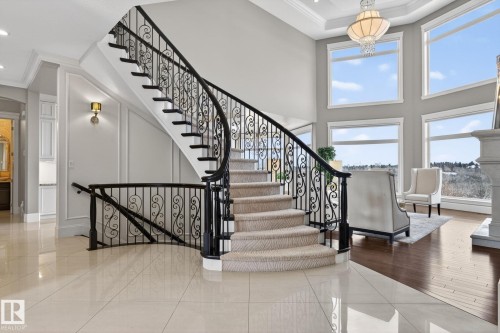 Elegant curved staircase with ornate wrought iron balusters and carpeted treads - 1413 Woodward Crescent, Edmonton, AB - Indoor Photo Showing Other Room
