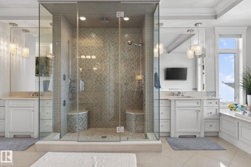 This bathroom features a spacious glass-enclosed shower with mosaic tile, two separate vanity areas with white cabinetry, and a window providing natural light - 1413 Woodward Crescent, Edmonton, AB - Indoor Photo Showing Bathroom