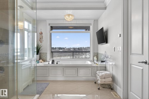 Spacious bathroom featuring a large soaking tub with a view, a glass-enclosed shower, tile flooring, and a chandelier light fixture - 1413 Woodward Crescent, Edmonton, AB - Indoor Photo Showing Bathroom