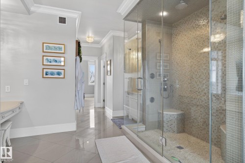 This bathroom features a spacious glass-enclosed shower with mosaic tile walls and a pebble floor, complete with a built-in bench and modern shower fixtures - 1413 Woodward Crescent, Edmonton, AB - Indoor Photo Showing Bathroom