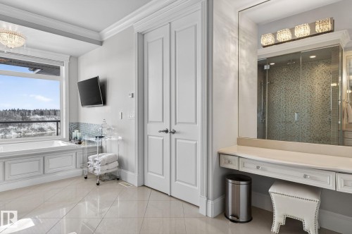 The bathroom features a built-in bathtub with a large window, a spacious vanity with a mirror and decorative lighting, and a glass-enclosed shower with tiled walls - 1413 Woodward Crescent, Edmonton, AB - Indoor Photo Showing Other Room