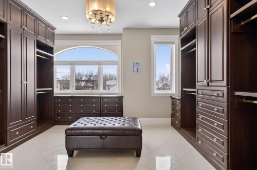 This space features extensive dark wood cabinetry, a large arched window, and recessed lighting - 1413 Woodward Crescent, Edmonton, AB - Indoor Photo Showing Bedroom