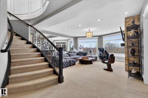 This room features a grand curved staircase with ornate black wrought iron railings and carpeted steps - 1413 Woodward Crescent, Edmonton, AB - Indoor Photo Showing Other Room