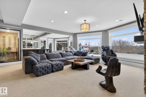 Spacious living area featuring light-colored carpeting, a recessed ceiling with lighting, and large windows offering exterior views - 1413 Woodward Crescent, Edmonton, AB - Indoor