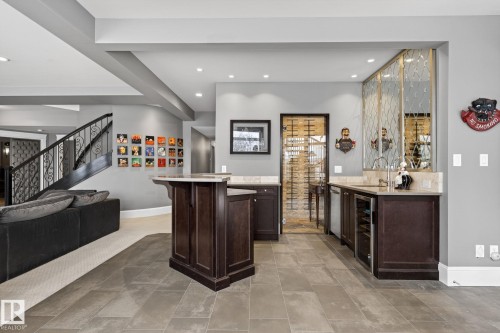 This property features a wet bar with dark wood cabinetry, a built-in wine cooler, and a sink with a wall-mounted mirror accent - 1413 Woodward Crescent, Edmonton, AB - Indoor Photo Showing Other Room