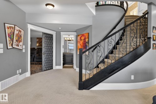 A grand staircase with ornate wrought iron balusters and a dark wood banister creates a striking focal point - 1413 Woodward Crescent, Edmonton, AB - Indoor Photo Showing Other Room