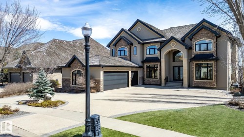 Stately stucco and stone-clad residence featuring a multi-gabled roofline and an arched portico entry - 1413 Woodward Crescent, Edmonton, AB - Outdoor With View