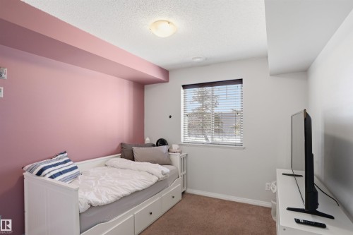 This room features a window with blinds, a white daybed with storage drawers, and a pink accent wall - 115 6925 199 Street, Edmonton, AB - Indoor Photo Showing Bedroom